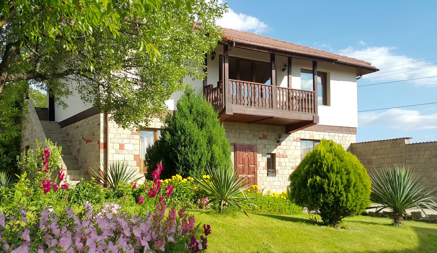 Къща за гости "Кьосев" в слънчев ден със зеленина и цветя